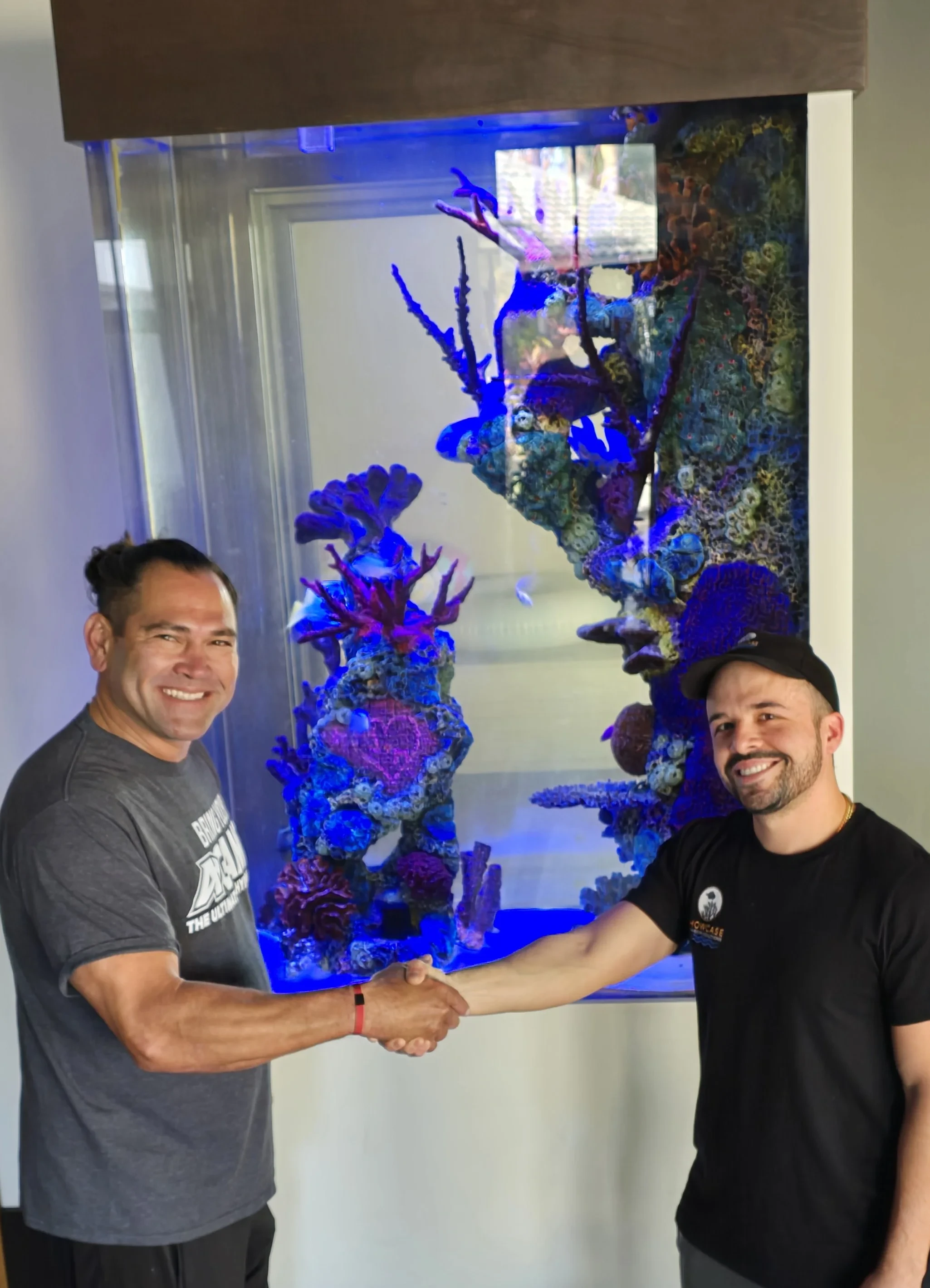 Kyle Garcia with a client beside a reef aquarium